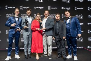 Grupo de seis pessoas - da Supply Brain e Grupo CBO - em um palco segurando troféus do Prêmio Inbrasc, posando para foto diante de um painel preto com a marca do evento.