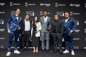 Equipe Supply Brain e representantes da Alpargatas posam no palco do Prêmio Inbrasc 2025 diante do painel oficial do evento.